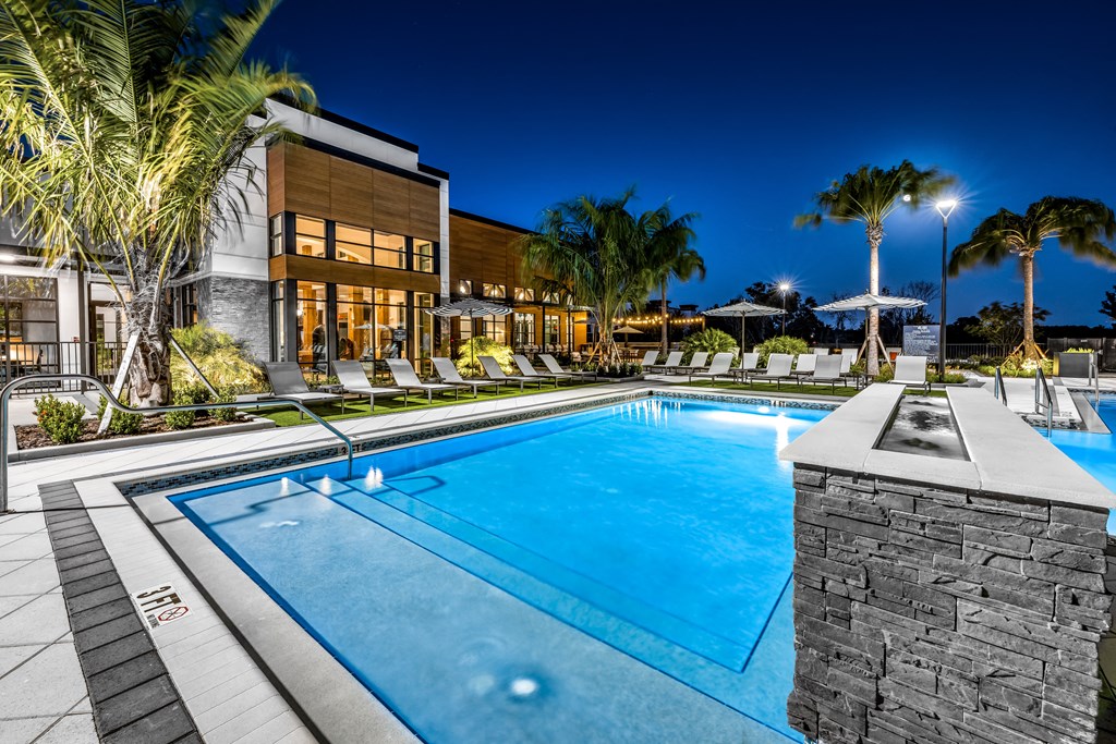 a swimming pool in front of a hotel at night