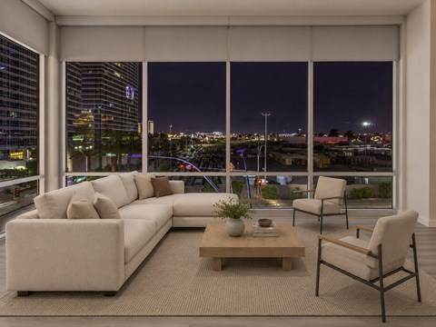 A modern living room with a large window overlooking the city at night.