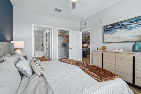 A bedroom with a large bed and a painting on the wall.