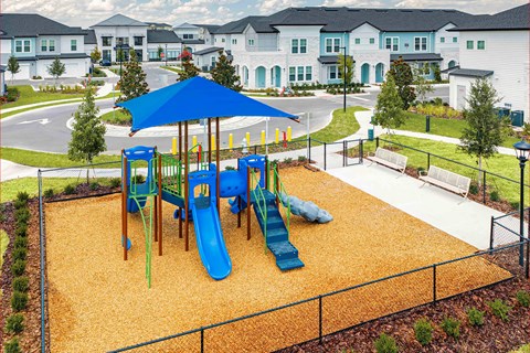 A playground with a blue umbrella and a yellow slide.