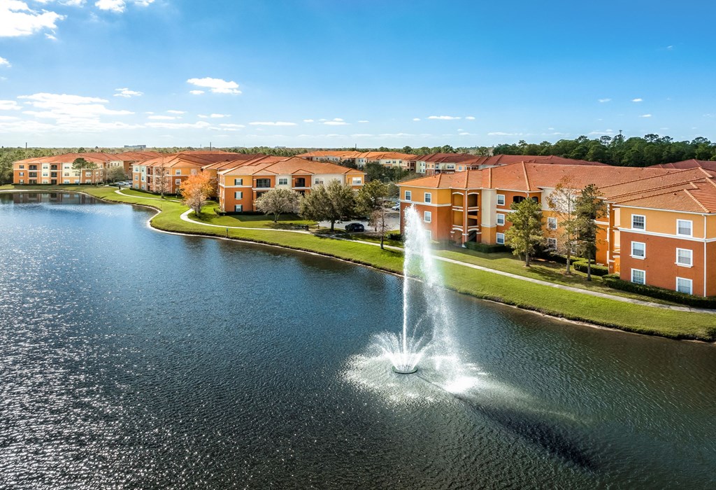 a fountain in the middle of a lake with an apartment complex in the background