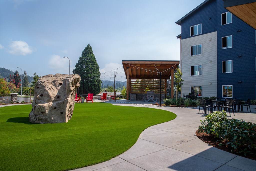 a large rock sits in the middle of a grassy area with a building in the backgroundat Scouter's Mountain, Happy Valley, OR