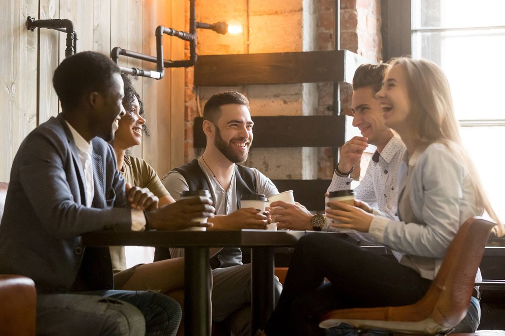 a group of people sitting around a table drinking coffee