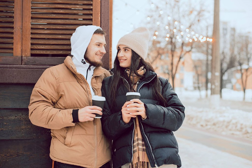 a man and a woman drinking coffee on the street in the snow