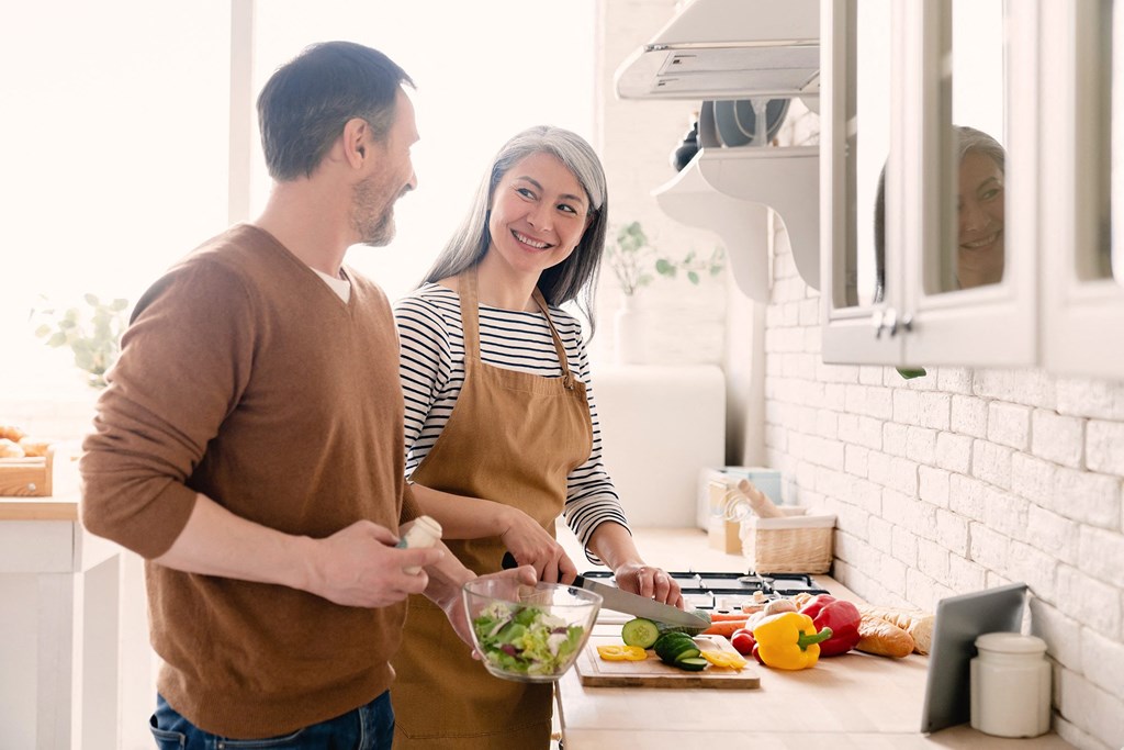 a man and a woman in a kitchen preparing food