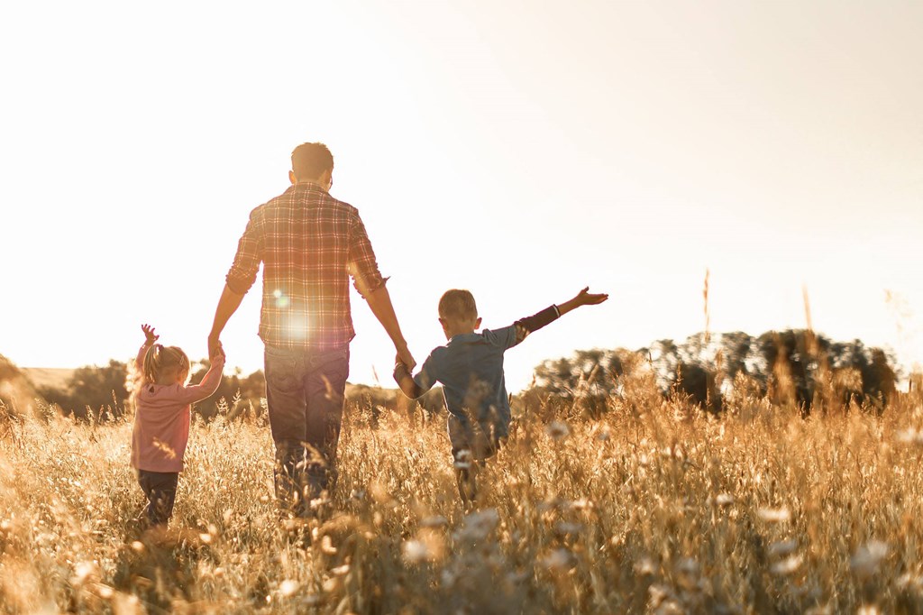 a man and two children walking through a field