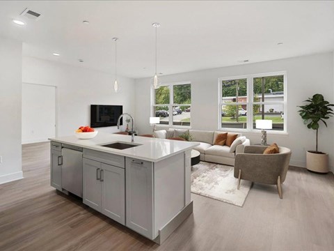 A modern kitchen with a large island and a couch in the living room.