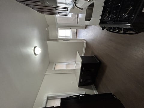 A white wall with a round light fixture and a skylight above a window.