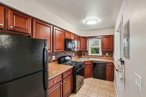 A kitchen with brown cabinets and black appliances.