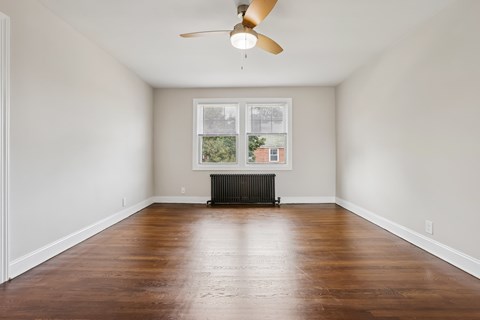 A room with a ceiling fan and a window with a view of a building outside.