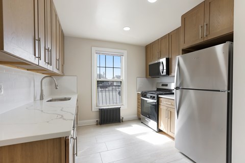A kitchen with a refrigerator, microwave, and oven.