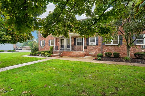 A red brick house with a green lawn in front.
