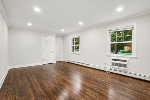 A room with wooden floors and a window showing trees outside.