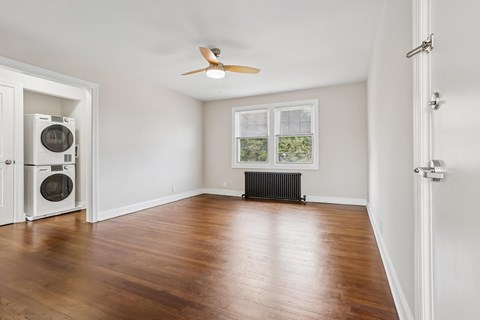 A room with a ceiling fan and a window with a view of a garden.