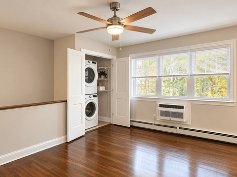 A room with a ceiling fan and a washer and dryer in the doorway.