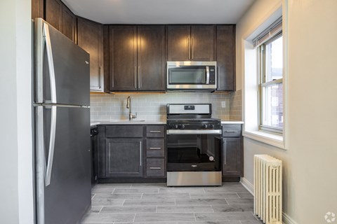A modern kitchen with dark wood cabinets and stainless steel appliances.