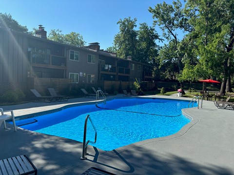 A swimming pool surrounded by a concrete patio and a building in the background.