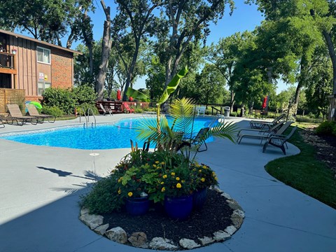 A pool surrounded by a small garden and a patio area.