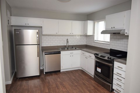 A kitchen with white cabinets and a stainless steel refrigerator.