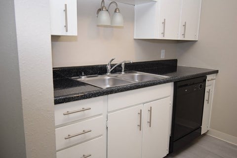 a kitchen with white cabinets and a sink and a black counter top