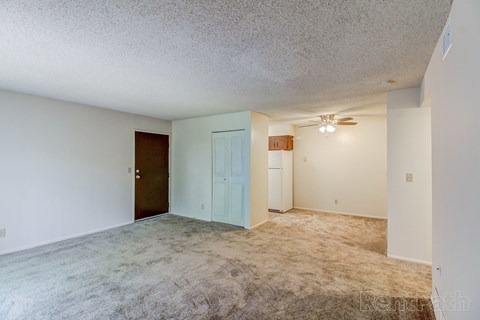 A room with a carpeted floor and a ceiling fan.