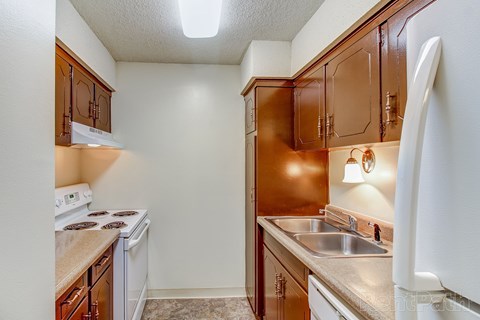 A kitchen with brown cabinets and a white refrigerator.