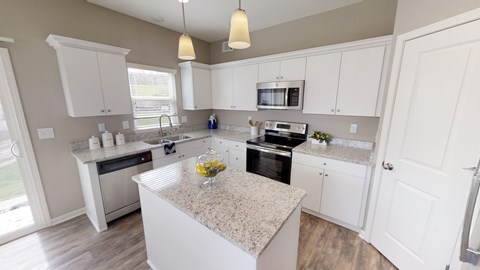 A kitchen with a granite countertop and white cabinets.