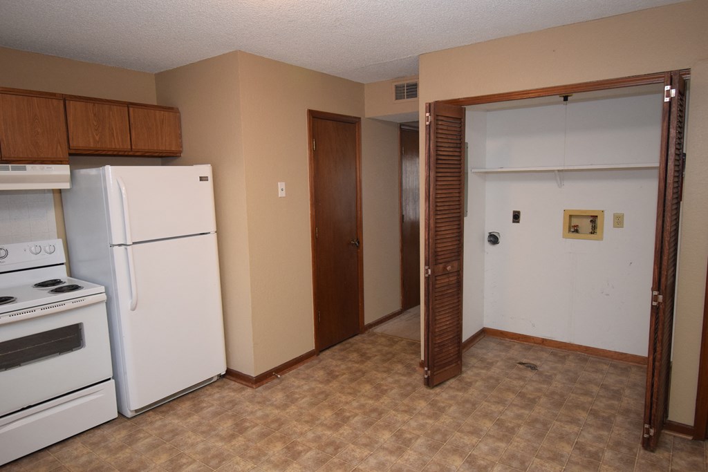 an empty kitchen with a refrigerator and a door to a closet
