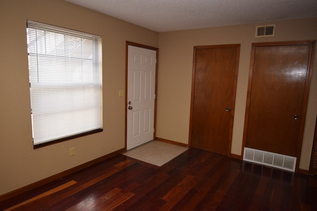 an empty room with wooden floors and a door and a window