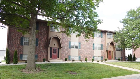 A red brick building with a tree in front.