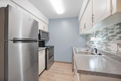 A kitchen with a stainless steel refrigerator, microwave, and oven.