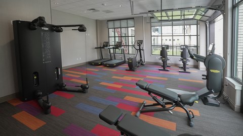 A gym with a variety of equipment including treadmills, weights, and exercise machines at Denver Metro Village Apartments, Denver, CO, 80204