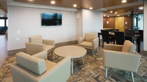 A living room with a couch, chairs, and a television.
