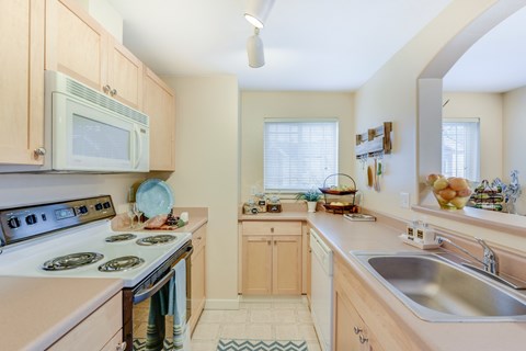 A kitchen with a stove, sink, and microwave at The Lodge at Peasley Canyon in Federal Way, Washington 98001