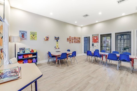 A room with a white table and blue chairs.