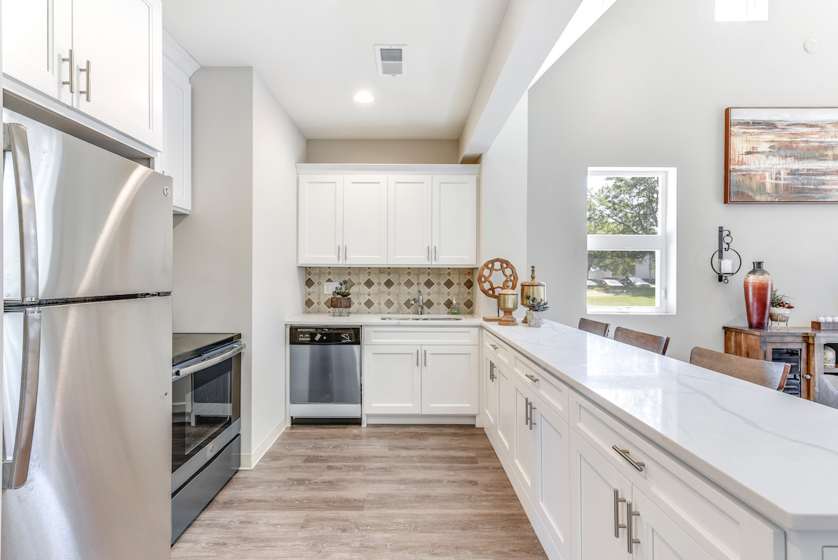 A modern kitchen with white cabinets and stainless steel appliances.