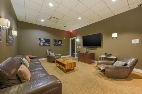 A living room with brown leather furniture and a flat screen TV mounted on the wall.