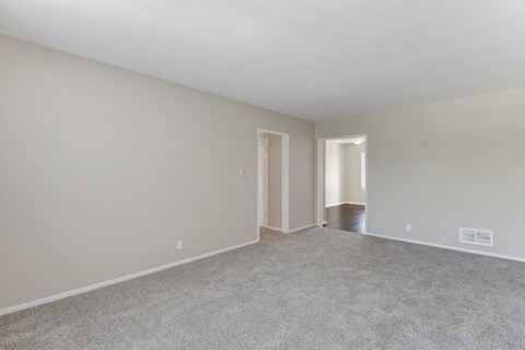 A spacious room with carpeted floor and two doors.