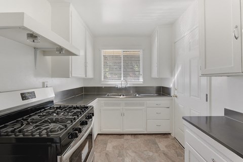 A kitchen with a black stove top oven and white cabinets.