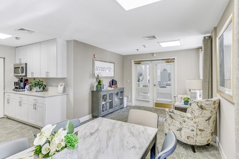 A well-lit, modern kitchen with a breakfast bar and a dining table set with a vase of flowers.