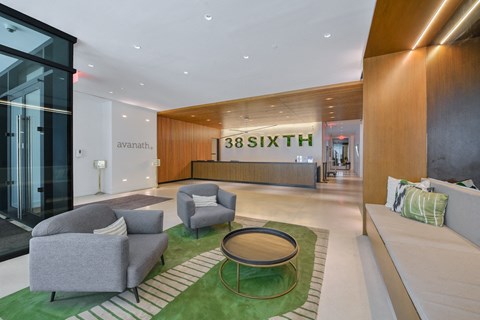 A modern living room with a green rug and grey couches.