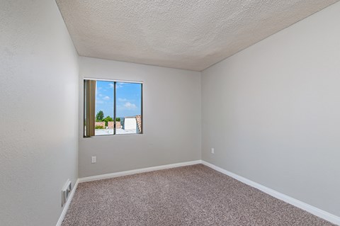A room with a window showing a view of a building and a blue sky.