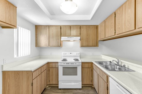 A kitchen with wooden cabinets and a white stove top oven.