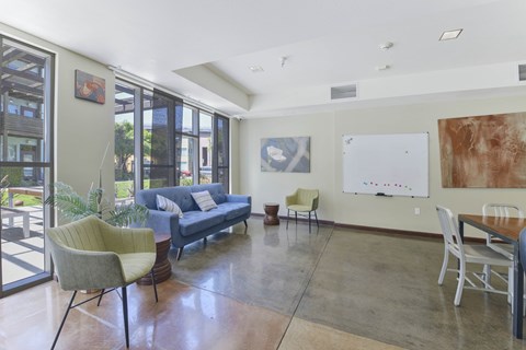 A living room with a blue couch and a whiteboard on the wall.