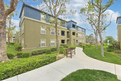 Apartment complex with a walkway and bench.