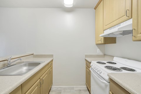 A kitchen with a white stove and a white sink.