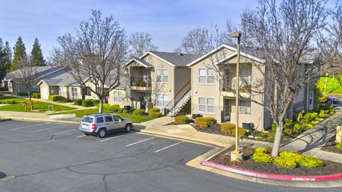 A car is parked in a parking lot in front of a building.