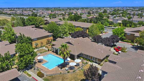 A bird's eye view of a residential area with houses, a swimming pool, and trees. at Hurley Creek Apartment Homes, Sacramento, CA, 95834