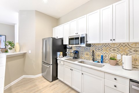 A kitchen with white cabinets and a black fridge.