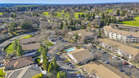 A bird's eye view of a residential area with houses and a pool.